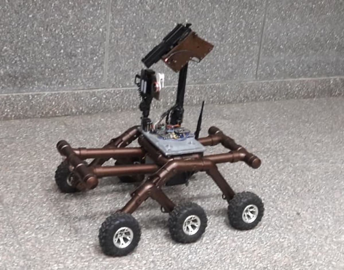 The UGV — a six-wheeled robot with a mounted handgun, camera and antenna.